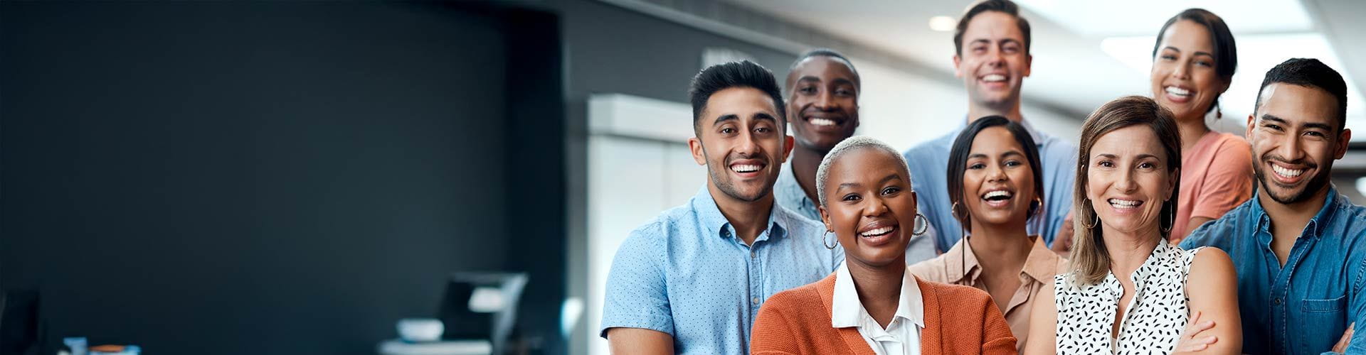 Groupe de 8 personnes dans une entreprise croisant les bras et souriant devant l’objectif