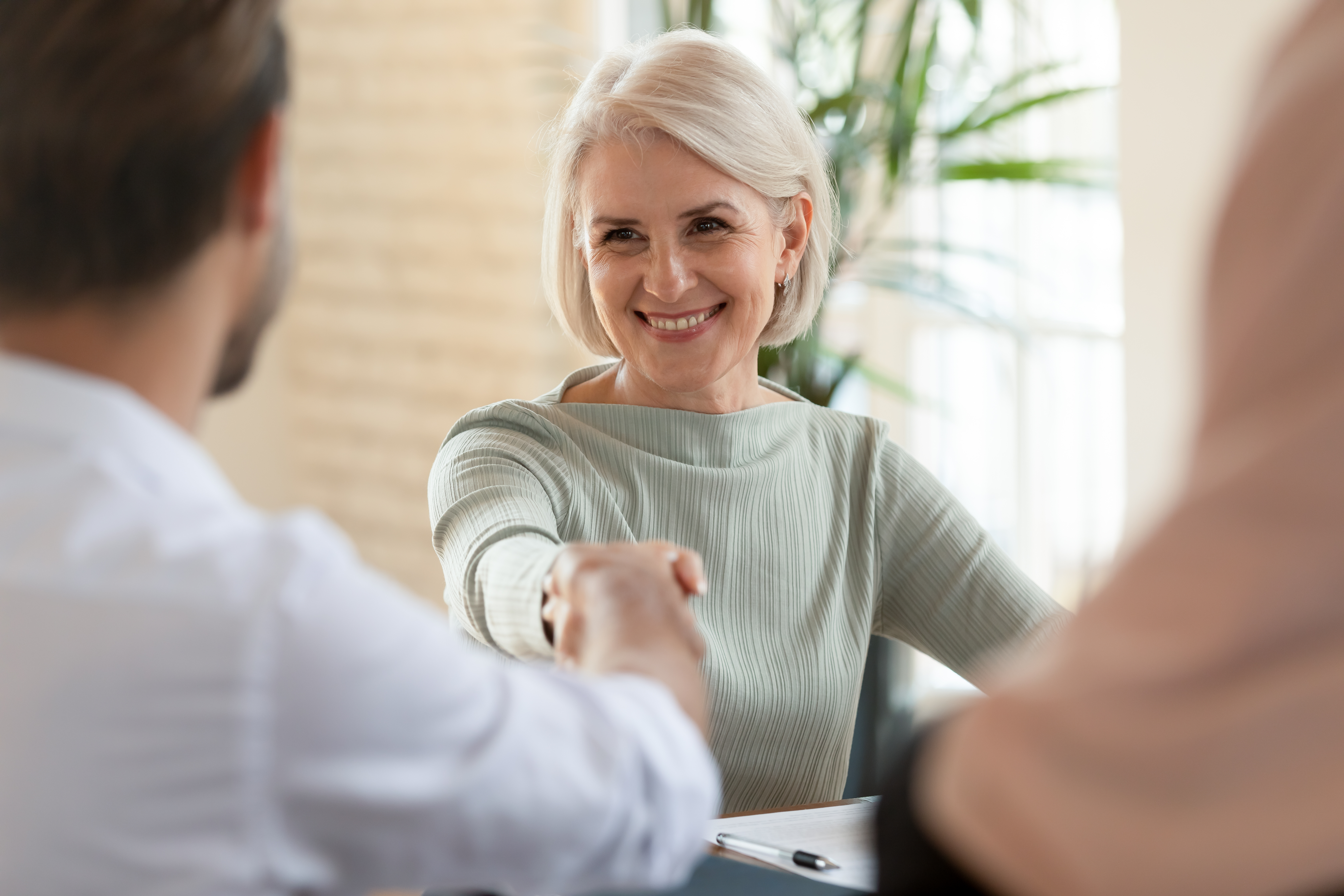 Lors d’une réunion, une experte des solutions de ressources humaines d’Adecco serre la main d’un client satisfait.
